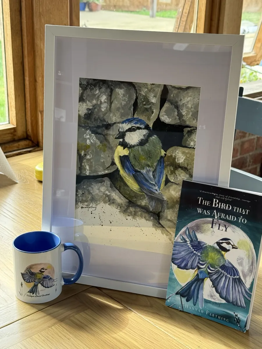 The framed Bluey painting displayed with The Bird That Was Afraid to Fly book and mug.