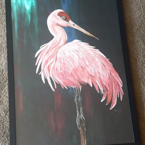 Pink Heron: acrylic painting of a pink wading bird with ruffled feathers against a dark background, in a black frame.